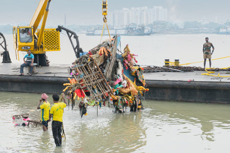 KOLKATA, WEST BENGAL, INDIA - 30 SEPTEMBER 2017: Grabage of immersed Goddess Durga idol is being lifted up from holy river Ganges by crane.のeditorial素材