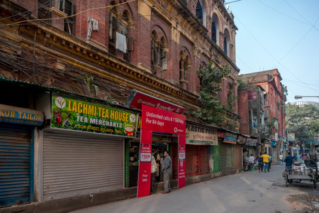 KOLKATA, WEST BENGAL, INDIA - DECEMBER 24TH 2017 : Three storied old house with vintage styled windows, walls made of red coloured bricks and modern retail shops - a typical north kolkata house.のeditorial素材