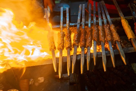 Spicy chicken seekh kababs are being grilled with heat in barbeque with metal skewers,at evening for sale as street food in Old Delhi market. It is famous for spicy Indian non vegetarian street foods.の写真素材