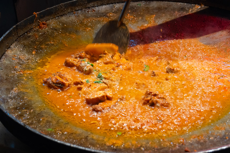 Spicy chicken curry is being prepared with heat at evening for sale as street food in Old Delhi market. The place is very famous for spicy Indian non vegetarian street foods.の写真素材