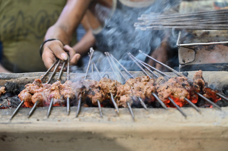 Chicken seekh kababs are being grilled with heat in barbeque with metal skewers,at evening for sale as street food in Kolkata, India. India is famous for spicy Indian non vegetarian street foods.の写真素材
