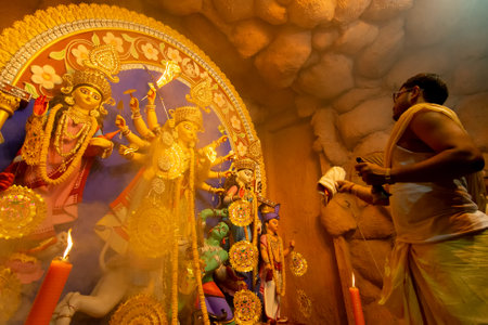 Kolkata, India - October 16, 2018 : Hindu Priest worshipping Goddess Durga with sari, Indian woman's...