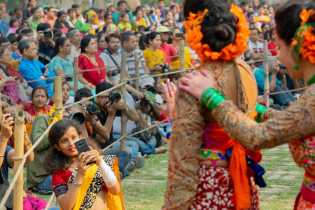 Kolkata, India- 1st March 2018: Girl taking picture of dancers dressed in colourful sari...