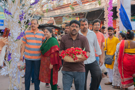 Kolkata, West Bengal, India - 15th April 2019 : Young man carrying hibiscus flowers, idols of Goddess Laxmi and Lord Ganesh for worship, in a bucket. Image shot at Kalighat, Bengali New year,のeditorial素材