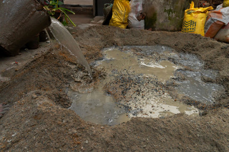 Kolkata, West Bengal, India - 6th January 2020 : Indian labour mixing cement and water manually on floor using a shovel. Stcok image.のeditorial素材