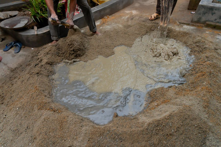 Kolkata, West Bengal, India - 6th January 2020 : Indian labour mixing cement and water manually on floor using a shovel. Stcok image.のeditorial素材