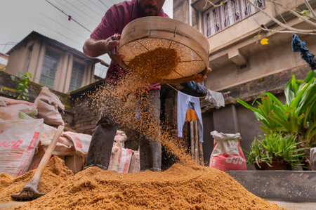 Howrah, West Bengal, India - 6th January 2020 : Indian labour separating sand and gravel manually using a sieve, for using the sand for cementing work, Image shot from low angle.のeditorial素材