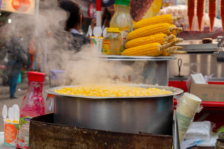 Kolkata, West Bengal, India - 29th December 2019 : Street vendor selling boiled baby corn on wheelcart to passer by customer. A popular vegetable street food in Kolkata.のeditorial素材