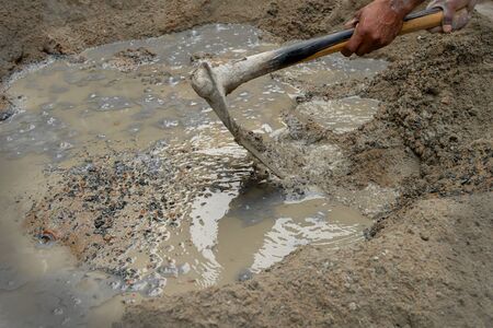 Indian labour mixing cement and water manually on floor using a shovel. Stock image.の写真素材