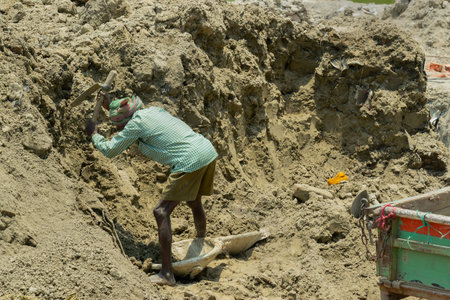 Howrah, West Bengal, India - 7th May 2017 : Indian male worker digging soil at buliding construction site. Shot from distance at day time. India has a huge population of daily wage earners.のeditorial素材
