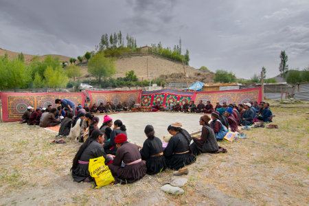 Mulbekh, Ladakh, India - 2nd September 2014 : Ladakhi people in traditional dresses, gathered for religious festival. Himalayan mountains in the background.のeditorial素材