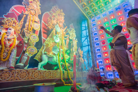 Howrah, West Bengal, India - 5th October 2019 : Hindu Bengali priests worshipping Goddess Durga with conch shell, covered under Holy smoke during Durga Puja . Shot under colored light.のeditorial素材