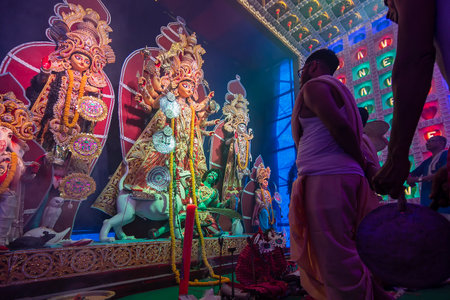 Howrah, West Bengal, India - 5th October 2019 : Kansor ghonta is played by devotee while Hindu Bengali priest worships Goddess Durga, Durga aarti under Holy smoke during Durga Puja shot at night.のeditorial素材