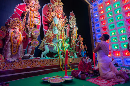 Howrah, West Bengal, India - 5th October 2019 : Hindu Bengali purohit kneeling down in respect and parying to Goddess Durga inside Durga Puja pandal,. Famous Durga Puja festival of Hinduism.のeditorial素材
