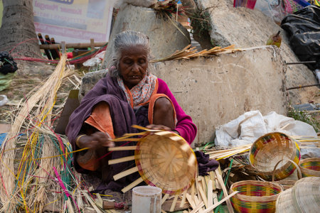 Kolkata, West Bengal, India - 31st December 2018 : Senior Bengali woman making wicker baskets for...