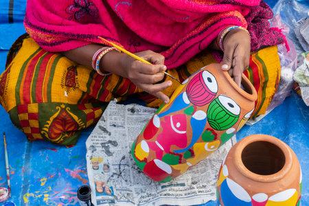 Female Indian artist painting colorful terracotta pots, works of handicraft, for sale during Handicraft Fair in Kolkata.のeditorial素材