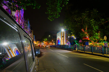 Kolkata, West Bengal, India - 23rd October, 2020 : Reflection of decorated Durga Puja pandal at night, beside street of Kolkata, on car window. Biggest festival of Hinduism celebrated worldwide..のeditorial素材