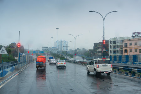 Howrah, West Bengal, India - 17th August 2019 : Image shot through raindrops falling on car windshield , wet glass, traffic at 2nd Hoogly bridge. Monsoon stock image.のeditorial素材
