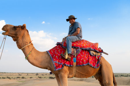 Thar desert,Rajasthan,India-15th October 2019 : Indian male tourist riding a camel in the desrt, Camels, Camelus dromedarius, into sand dunes. Camel riding is popular for travellers.のeditorial素材