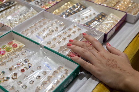 Kolkata, West Bengal, India - 12th October 2022 : Beautiful mehendi design applied over hand of a young lady , checking out jewellery in retail shop. Nice ornaments are beings sold to ladies.のeditorial素材
