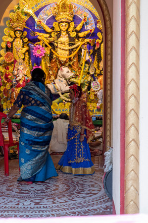 Howrah,India -October 26th,2020 : Bengali sari clad mother, showing Goddess Durga to child, Durga...