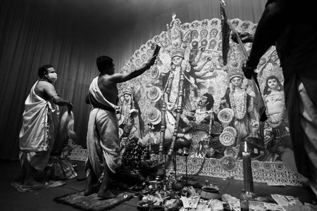 Howrah, India -October 13, 2021 : Hindu Priests worshipping Goddess Durga with Shari, ghanta, chamor and hand fan. Ashtami puja aarati - sacred Durga Puja ritual - shot at night.のeditorial素材