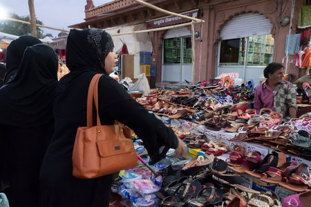 Jodhpur, Rajasthan, India - 20.10.2019 : Modern Muslim women with hijab, cloth wrapping their head, neck and shoulder are buying colorful Rajsathani ladies shoes at famous Sardar Market in Jodhpur.のeditorial素材