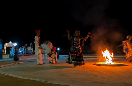 Thar desert, Rajasthan, India - October 15th 2019 : Rajasthani female dancer dancing, dressed with cultural dress of Rajasthan, at night. Male Musicians are playing music instruments in background.のeditorial素材