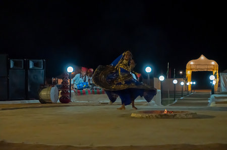 Thar desert, Rajasthan, India - October 15th 2019 : Rajasthani female dancer dancing, dressed with cultural dress of Rajasthan, at night. Male Musicians are playing music instruments in background.のeditorial素材