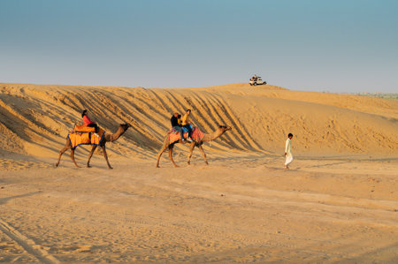Thar desert, Rajasthan, India - 16.10.2019 : Cameleer taking tourists on camel to watch sun rise. Dromedary, dromedary camel, Arabian camel, or one-humped camels are used for camel riding.のeditorial素材