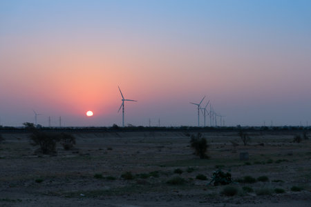 Dawn light in desert sky with Electrical power generating wind mills producing alterative eco friendly green energy for consumption by local people. Sun rise at Thar desert, Rajasthan, India.の写真素材