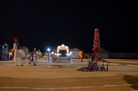 Thar desert, Rajasthan, India - October 15th 2019 : Female dancer dancing Bhavai, a folk dance, balancing six earthen pots on her head, picking up currency note from bottle, in cultural dress .のeditorial素材