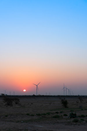 Dawn light in desert sky with Electrical power generating wind mills producing alterative eco friendly green energy for consumption by local people. Sun rise at Thar desert, Rajasthan, India.の写真素材