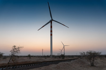 Pre dawn light in desert sky with Electrical power generating wind mills producing alterative eco friendly green energy for consumption by local people. Thar desert, Rajasthan, India.の写真素材