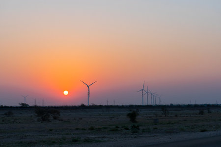 Dawn light in desert sky with Electrical power generating wind mills producing alterative eco friendly green energy for consumption by local people. Sun rise at Thar desert, Rajasthan, India.の写真素材