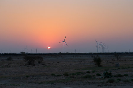 Dawn light in desert sky with Electrical power generating wind mills producing alterative eco friendly green energy for consumption by local people. Sun rise at Thar desert, Rajasthan, India.の写真素材
