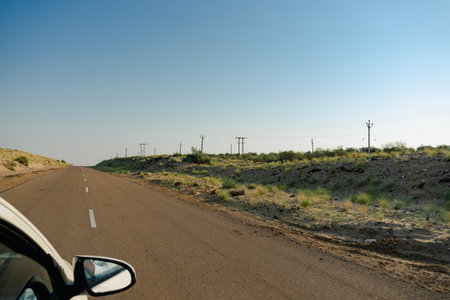 White car running through empty high road or national high way passing through the desert. Distant horizon, Hot summer at Thar desert, Rajasthan, India.の写真素材