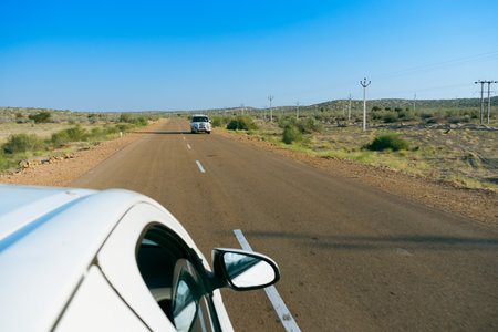 White car running through empty high road or national high way passing through the desert. Distant horizon, Hot summer at Thar desert, Rajasthan, India.の写真素材