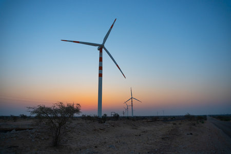 Pre dawn light in desert sky with Electrical power generating wind mills producing alterative eco friendly green energy for consumption by local people. Thar desert, Rajasthan, India.の写真素材