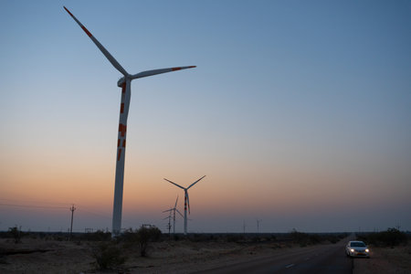 Pre dawn light in desert sky with Electrical power generating wind mills producing alterative eco friendly green energy for consumption by local people. Thar desert, Rajasthan, India.の写真素材