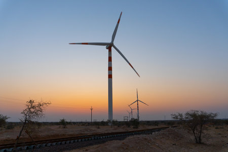 Pre dawn light in desert sky with Electrical power generating wind mills producing alterative eco friendly green energy for consumption by local people. Thar desert, Rajasthan, India.の写真素材