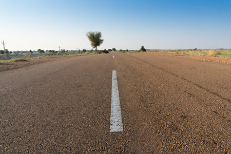 Morning in desert with empty high road or national high way passing through the desert. Distant horizon, Hot summer at Thar desert, Rajasthan, India.の写真素材