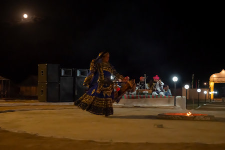 Thar desert, Rajasthan, India - October 15th 2019 : Rajasthani female dancer dancing, dressed with cultural dress of Rajasthan, at night. Moon rise in the background.のeditorial素材