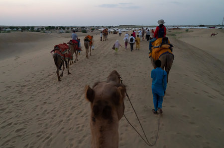 Thar desert, Rajassthan, India - October 15th 2019 : Tourists riding camels at sand dunes of Thar desert. Camel riding is a favourite activity amongst all tourists visiting here,のeditorial素材