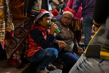 Kolkata, West Bengal, India - 26.12.2018 : Young boy enjoying drink with red santa claus hats enjoying themselves at illuminated and decorated park street with lights with year end festive mood.のeditorial素材