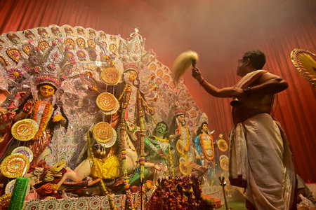 Howrah, India -October 13, 2021 : Hindu Priests worshipping Goddess Durga with ghanta, chamor and hand fan. Ashtami puja aarati - sacred Durga Puja ritual - shot at night.のeditorial素材