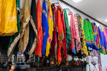 Jodhpur, Rajasthan, India - 19.10.2019 : Rajasthani womens clothes are hanging for sale , being displayed in a shop at famous Sardar Market and Ghanta ghar Clock tower in the evening.のeditorial素材