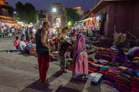 Jodhpur, Rajasthan, India - 19.10.2019 : Foreigners buying Rajasthani womens clothes being sold at Famous Sardar Market and Ghanta ghar Clock tower in the evening.のeditorial素材