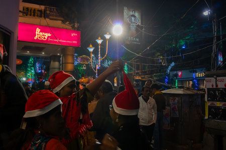 Kolkata, West Bengal, India - 25.12.2018 : Young ladies with red santa claus hats enjoying themselves at illuminated and decorated park street with lights with year end festive mood.のeditorial素材