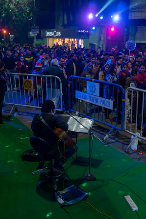 Kolkata, West Bengal, India - 25.12.2018 : Street singer singing festive mood songs while young people enjoying themselves at illuminated and decorated park street with year end joy and festive mood.のeditorial素材